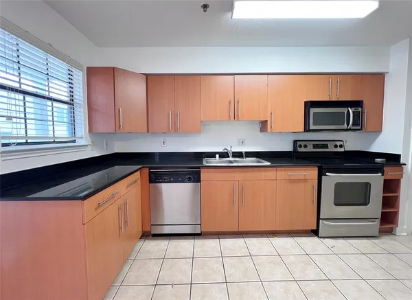 a kitchen with granite countertop a stove top oven cabinetry a sink and a microwave