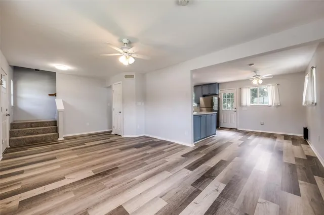 a view of an empty room with a window and wooden floor