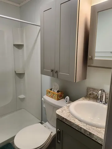 a bathroom with a granite countertop sink toilet and shower