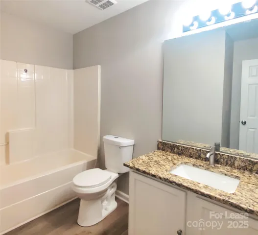 a bathroom with a granite countertop sink toilet and shower