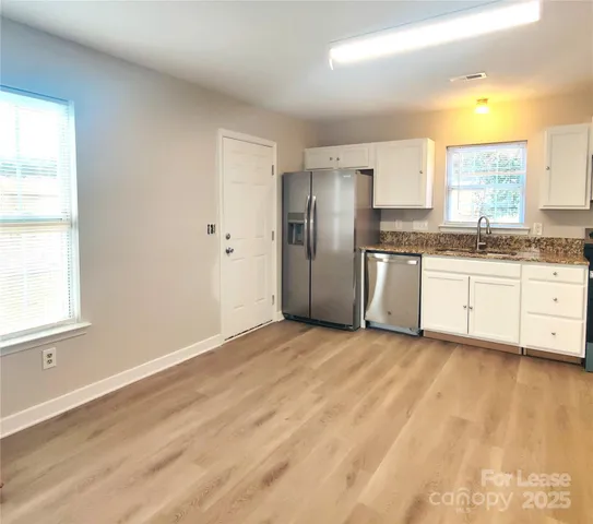 a view of a kitchen with stainless steel appliances granite countertop a refrigerator and a sink