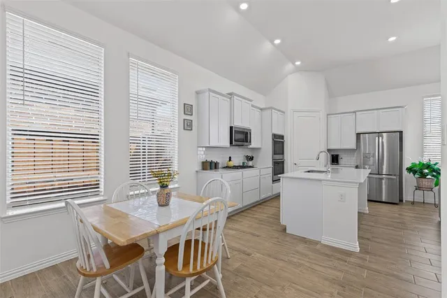 a kitchen that has a lot of cabinets a sink and appliances