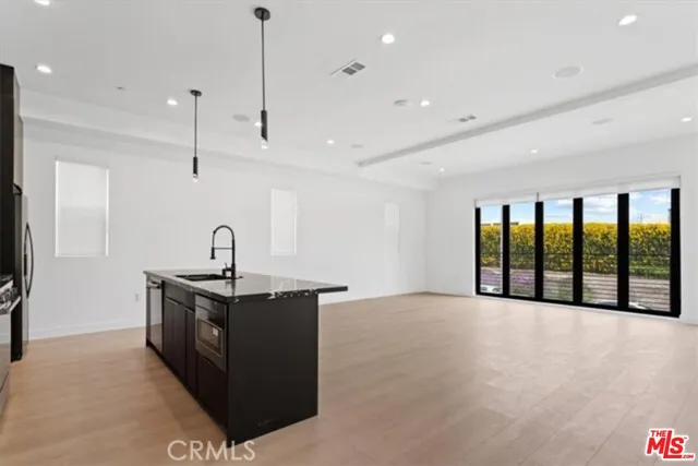 a view of a kitchen with stainless steel appliances granite countertop a sink and a refrigerator