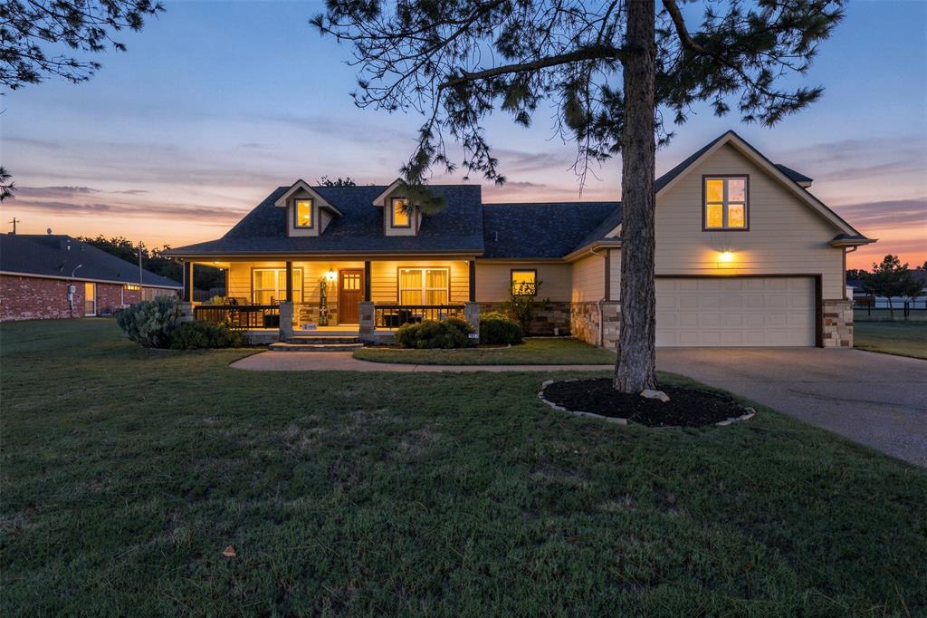 207 Dennis Road Lipan, TX 76462 - Photo 30 of 40 Craftsman-style home with dormer windows, stone accents, a covered front porch, and an attached two-car garage