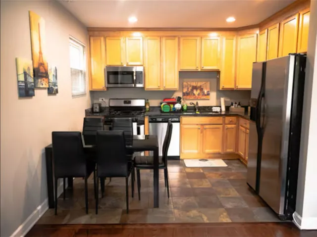 a kitchen with stainless steel appliances granite countertop a refrigerator a stove a microwave a dining table and chairs with wooden floor