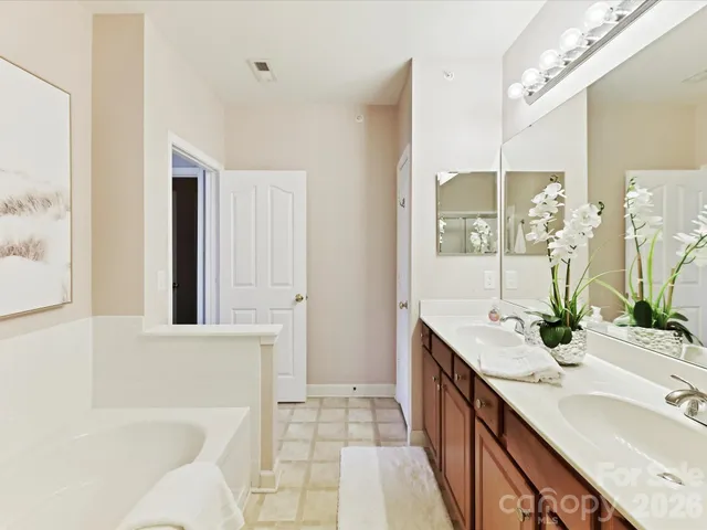 a bathroom with a double vanity sink a large mirror and a bathtub