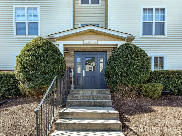 a view of a house with large windows and plants