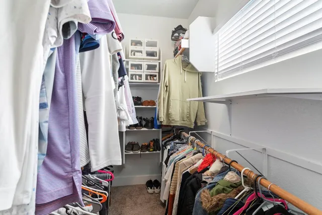 a view of walk in closet with clothes and shoes