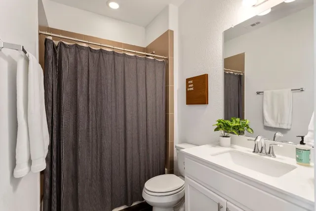 a bathroom with a sink a toilet a mirror and shower curtain