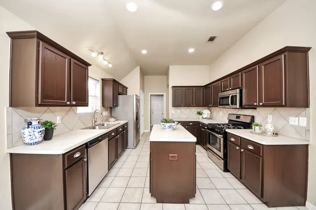 a kitchen with stainless steel appliances granite countertop a sink stove refrigerator and cabinets