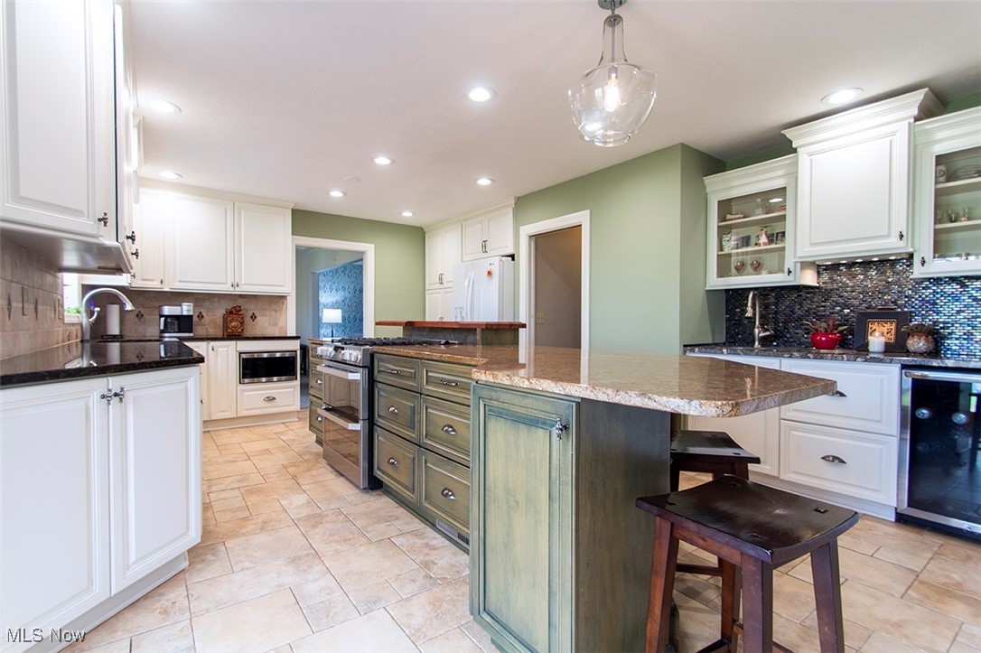 4041 Huffman Road Medina, OH 44256 - Photo 6 of 40 Kitchen with a kitchen island, white cabinetry, a breakfast bar area, beverage cooler, and stainless steel appliances