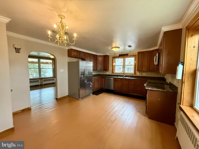 a living room with hard wood floors and kitchen