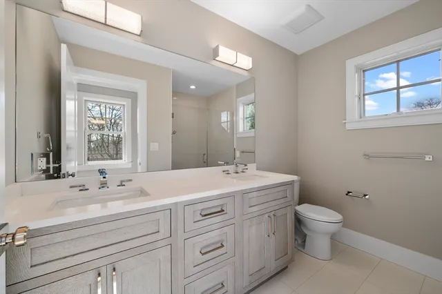 a bathroom with a double vanity sink toilet and a mirror