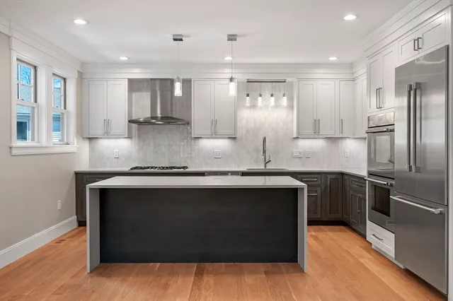 a kitchen with kitchen island stainless steel appliances a sink stove and refrigerator