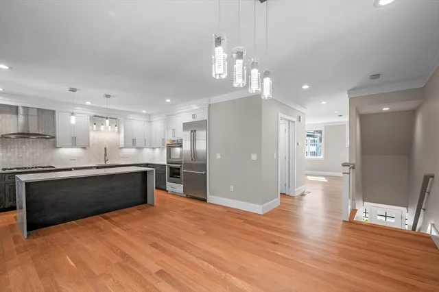 a large kitchen with stainless steel appliances kitchen island granite countertop a large counter top and stove top oven with wooden floor