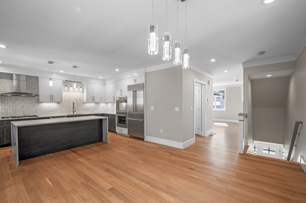 799 Heath Street, Unit 2 Brookline, MA 02467 - Photo 4 of 21 a large kitchen with stainless steel appliances kitchen island granite countertop a large counter top and stove top oven with wooden floor
