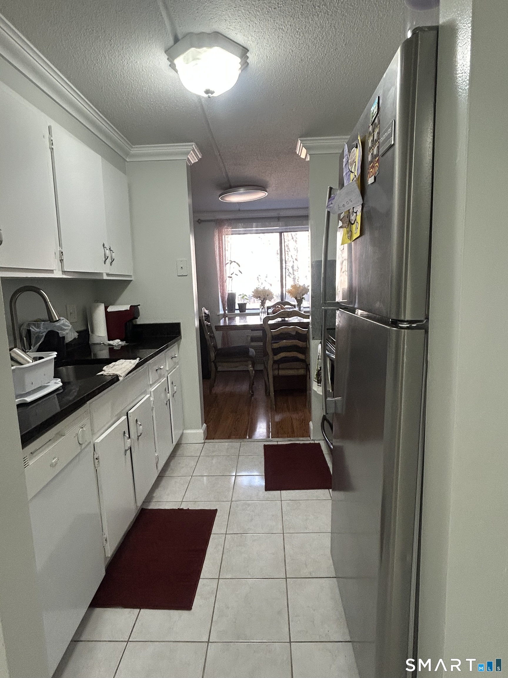 126 Triangle Street, Unit B13 Danbury, CT 06810 - Photo 6 of 20 a kitchen with a sink a refrigerator and chairs