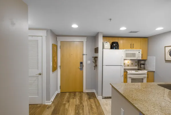 a view of a kitchen with a sink refrigerator and wooden floor