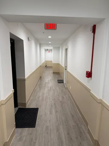 a view of an empty room with wooden floor and stairs