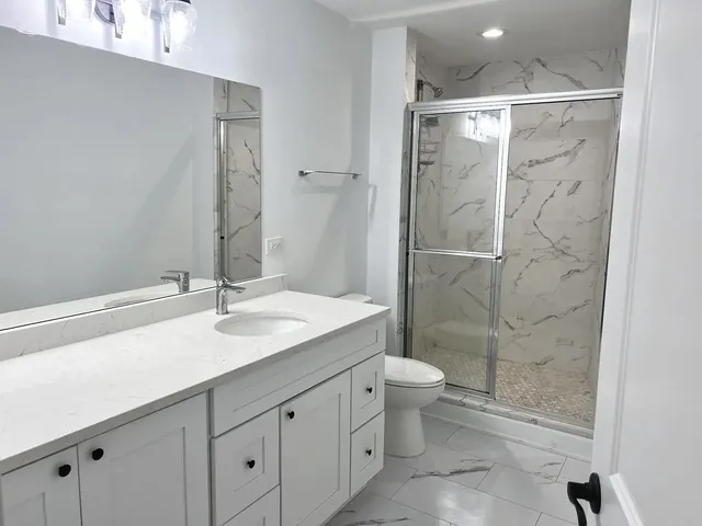a bathroom with a granite countertop sink a toilet and shower