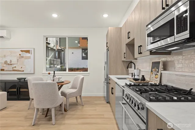 a kitchen with stainless steel appliances granite countertop a refrigerator a stove a sink dishwasher a dining table and chairs with wooden floor