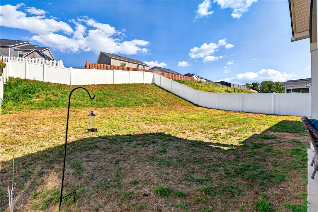 128 Whitman Way Easley, SC 29642 - Photo 26 of 34 Enjoy outdoor living in this spacious yard, featuring a white fence for privacy and a bright blue sky.