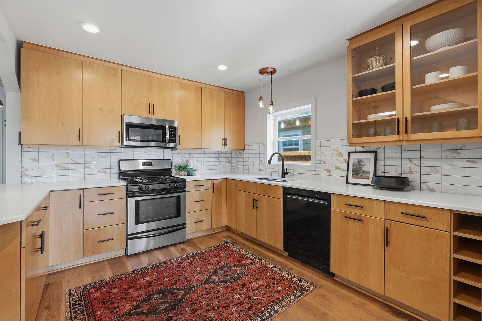 5509 Avenue F Austin, TX 78751 - Photo 16 of 40 The kitchen makes a statement with quartz countertops, a peninsula breakfast bar, designer tile, and stainless appliances.