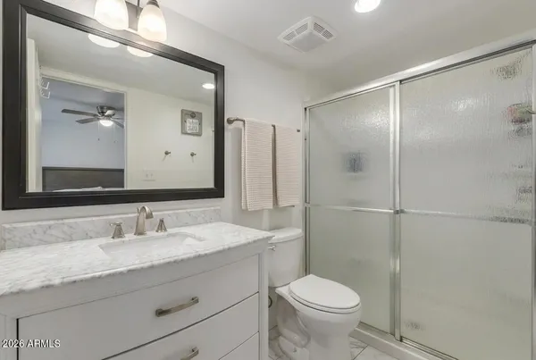 a bathroom with a granite countertop sink mirror vanity and toilet