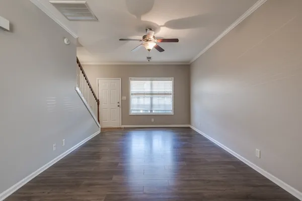 a view of an empty room with wooden floor and a window