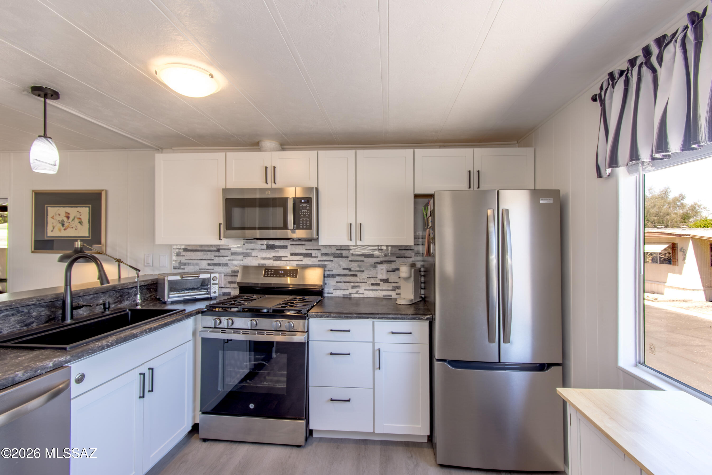 4550 North Flowing Wells Road, Unit 155 Tucson, AZ 85705 - Photo 10 of 40 a kitchen with refrigerator a stove a sink and a microwave