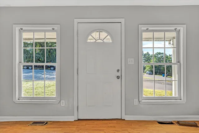 an empty room with wooden floor and windows