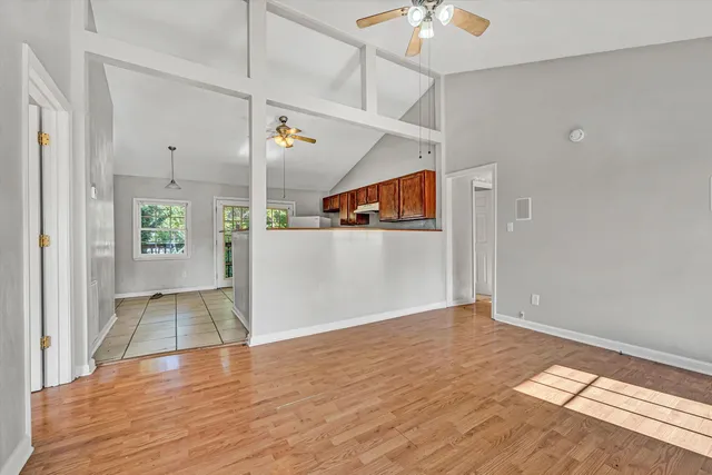 a view of a hallway with wooden floor and a living room
