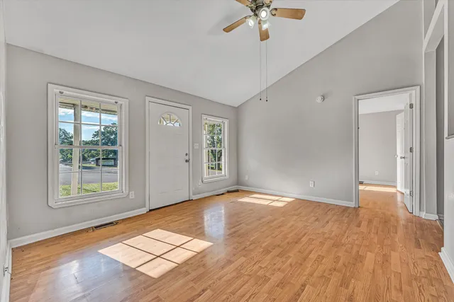 an empty room with wooden floor and windows