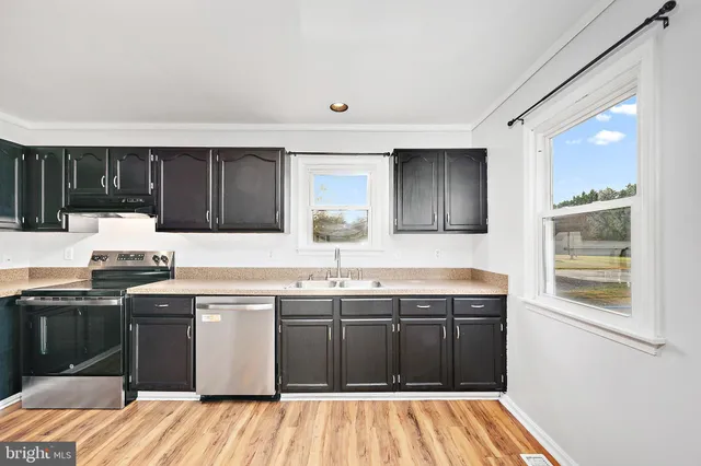 a kitchen with a sink a counter top space stainless steel appliances and cabinets