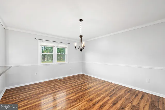an empty room with wooden floor and fan