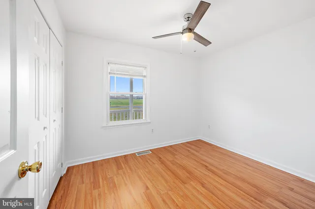 an empty room with wooden floor and fan