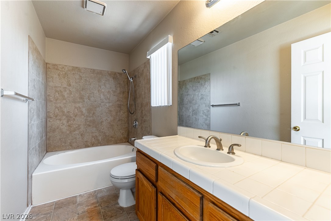 2657 Storey Circle Henderson, NV 89074 - Photo 11 of 12 This functional bathroom features a shower-tub combo, single vanity, and a large mirror, offering practicality and style.