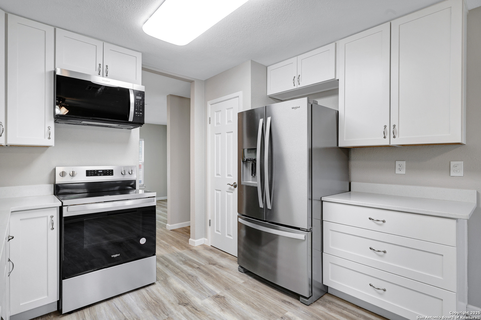 7103 Spring Point Street San Antonio, TX 78249 - Photo 17 of 28 a kitchen with stainless steel appliances white cabinets white stove a microwave and a refrigerator