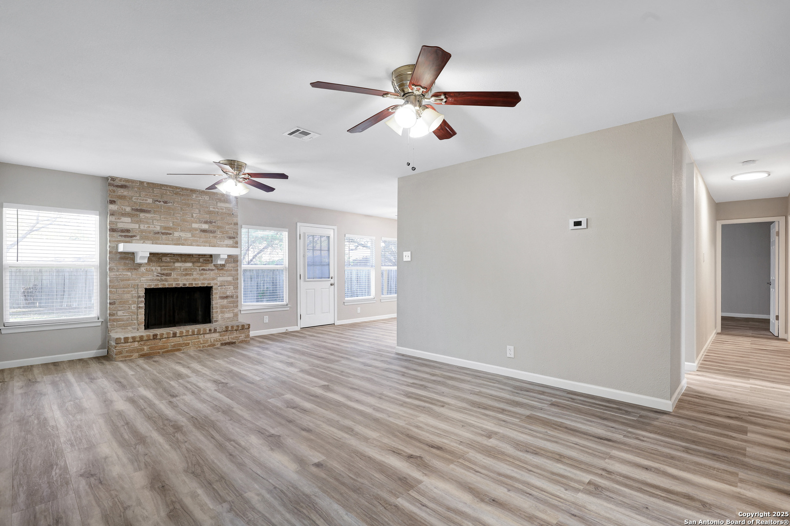 7103 Spring Point Street San Antonio, TX 78249 - Photo 3 of 28 wooden floor fireplace and windows in an empty room