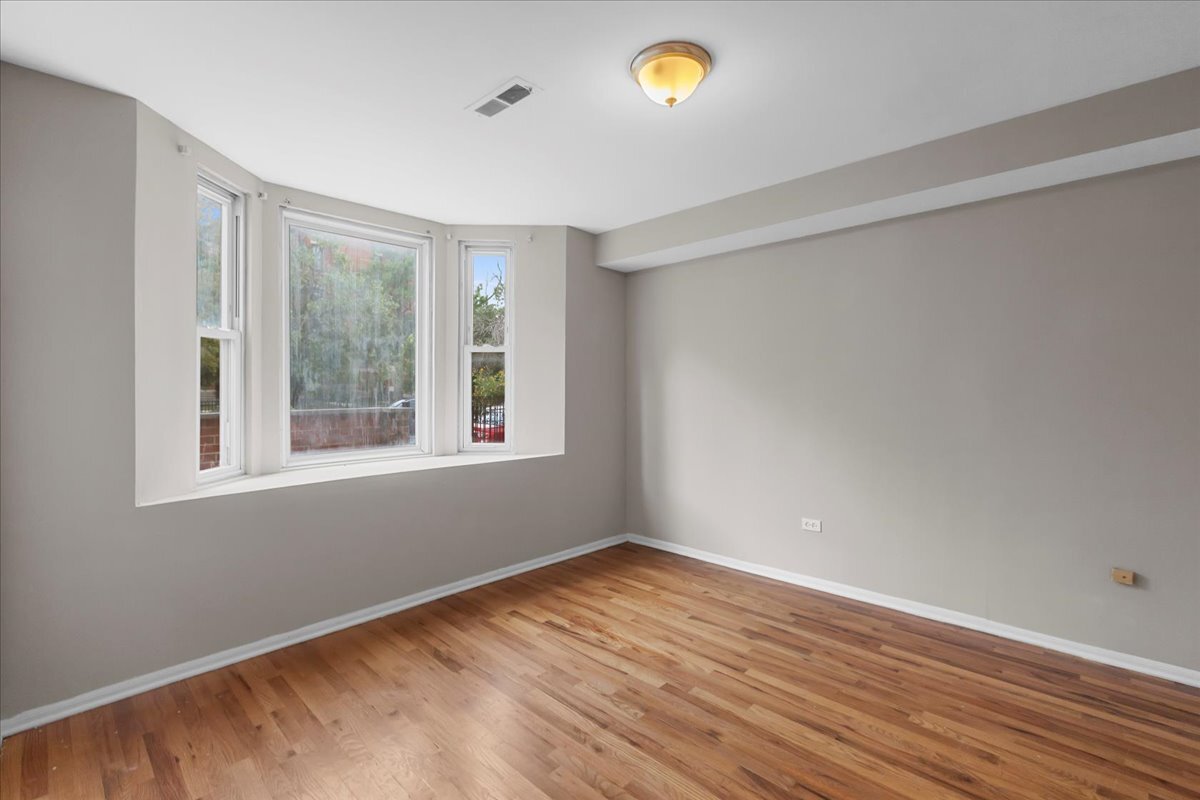 1464 West Ohio Street, Unit 1F Chicago, IL 60642 - Photo 5 of 10 an empty room with wooden floor and windows