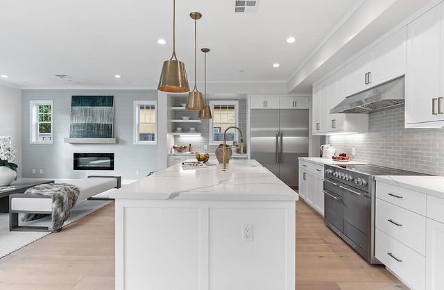 a kitchen with stainless steel appliances granite countertop a sink dishwasher a stove and white cabinets with wooden floor