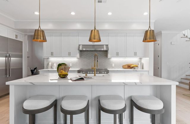 a kitchen with stainless steel appliances granite countertop a sink a stove a refrigerator and chairs with wooden floor