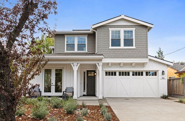 a view of a white house with large windows and a small yard