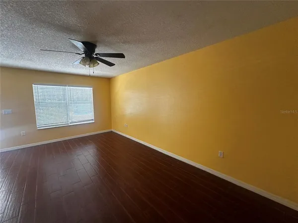 a view of empty room with wooden floor and fan