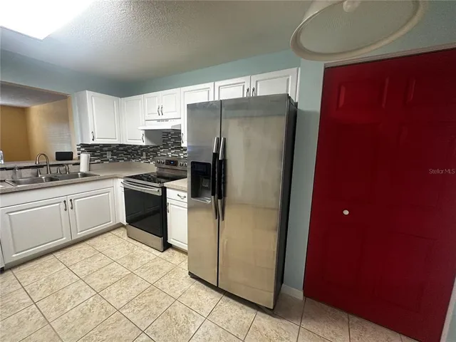 a kitchen with a refrigerator sink and cabinets