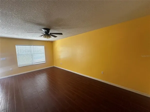 a view of empty room with wooden floor and fan