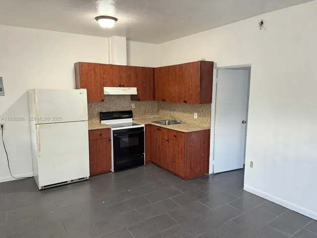 a kitchen with a stove a refrigerator and a more cabinets