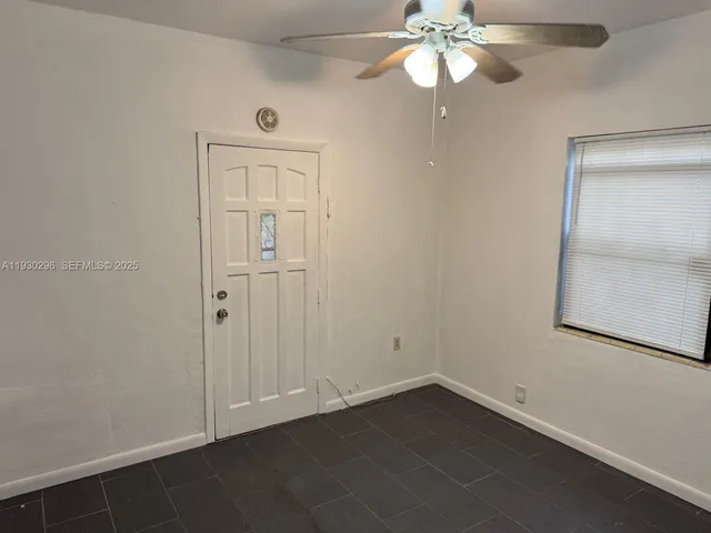 an empty room with a window and a chandelier fan