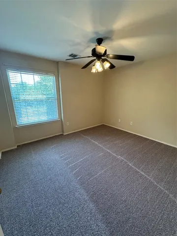 an empty room with a ceiling fan and a window