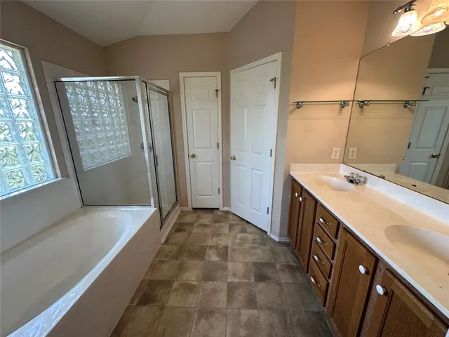 a bathroom with a double vanity sink and mirror with bathtub